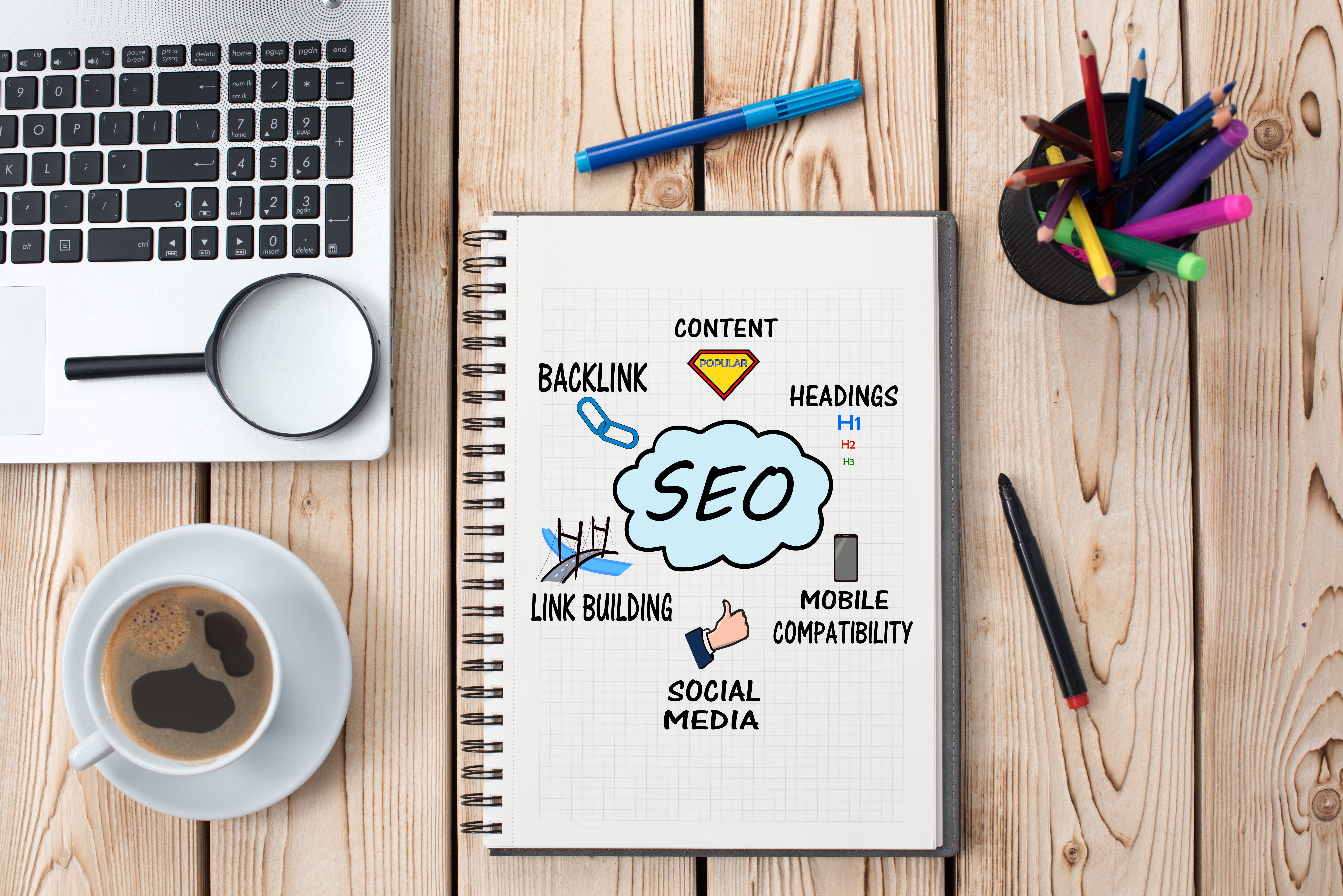 SEO for Search Engine Optimization doodled on a page promoting content, headings, mobile compatability, social media, and link building.